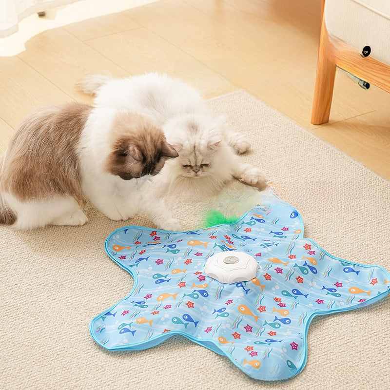 Cat playing with a blue fish-shaped mat on a carpeted floor.